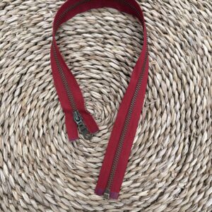 Bordeauxrode rits met metalen tandjes op gevlochten rieten ondergrond