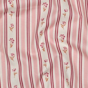 Textiel met roze en roomwitte strepen en kleine geborduurd bloemmotief in roze en oranje